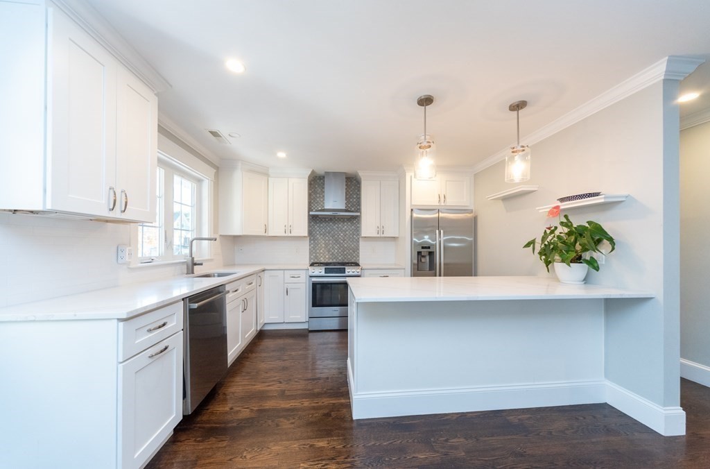 156 Ash Street, Unit 2 Waltham, MA 02453 - Photo 5 of 39 a kitchen with stainless steel appliances kitchen island granite countertop a stove a sink and a refrigerator