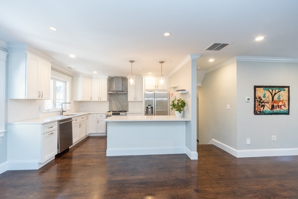 156 Ash Street, Unit 2 Waltham, MA 02453 - Photo 8 of 39 a large kitchen with granite countertop a large counter top a sink stainless steel appliances and cabinets
