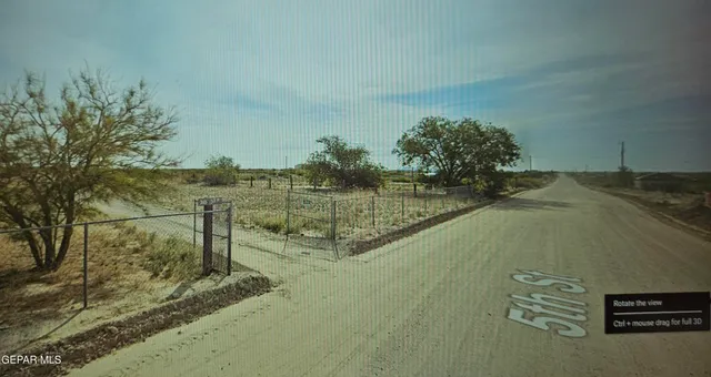 a view of a dry yard with wooden fence