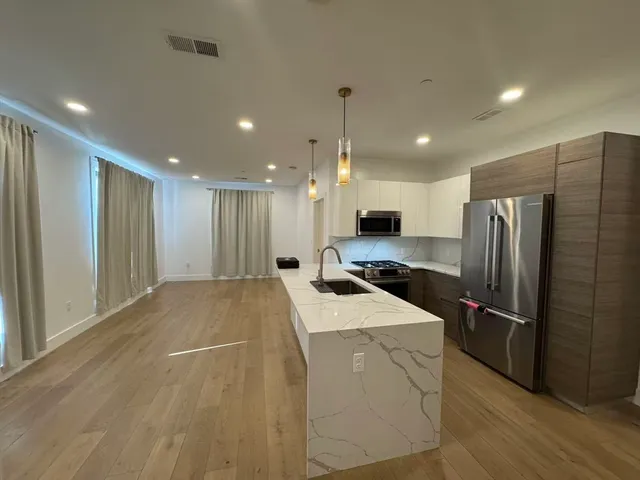 a open kitchen with stainless steel appliances kitchen island a sink a refrigerator and a fireplace