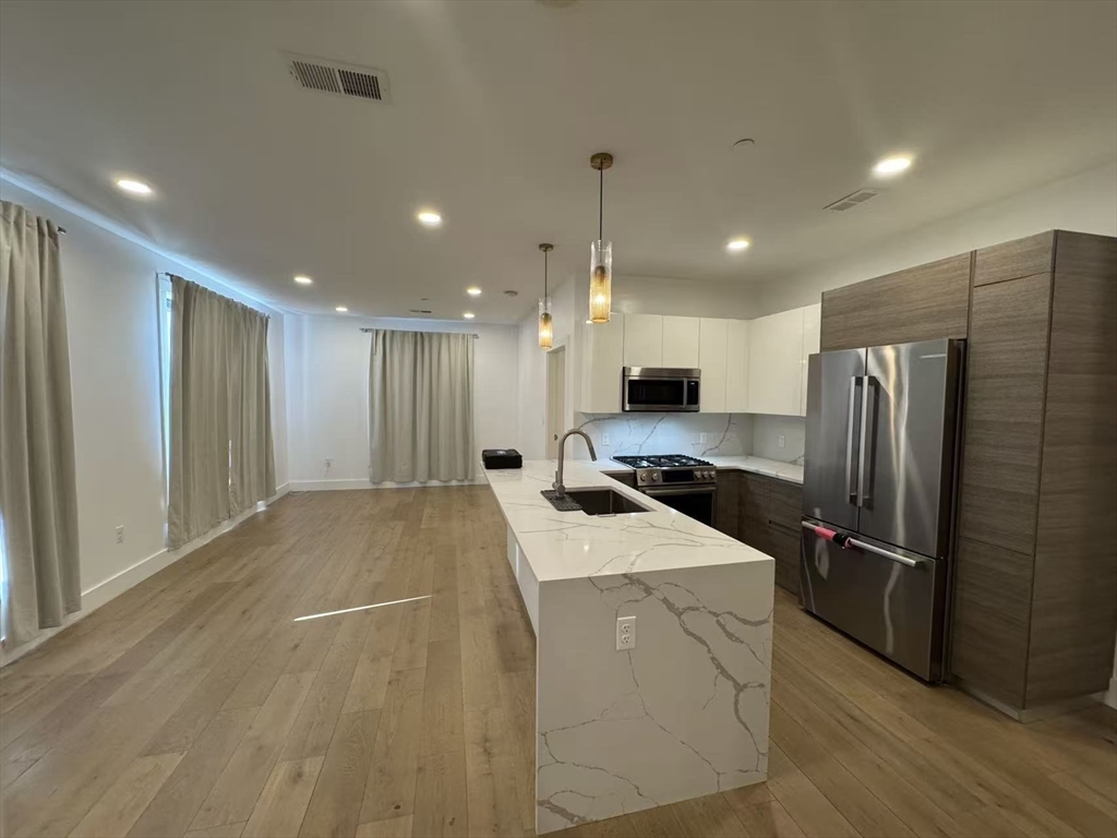 30 Penniman Road, Unit 307 Boston, MA 02134 - Photo 4 of 10 a open kitchen with stainless steel appliances kitchen island a sink a refrigerator and a fireplace