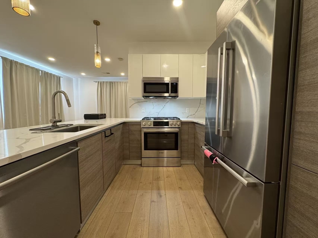 30 Penniman Road, Unit 307 Boston, MA 02134 - Photo 5 of 10 a kitchen with stainless steel appliances a refrigerator sink and microwave