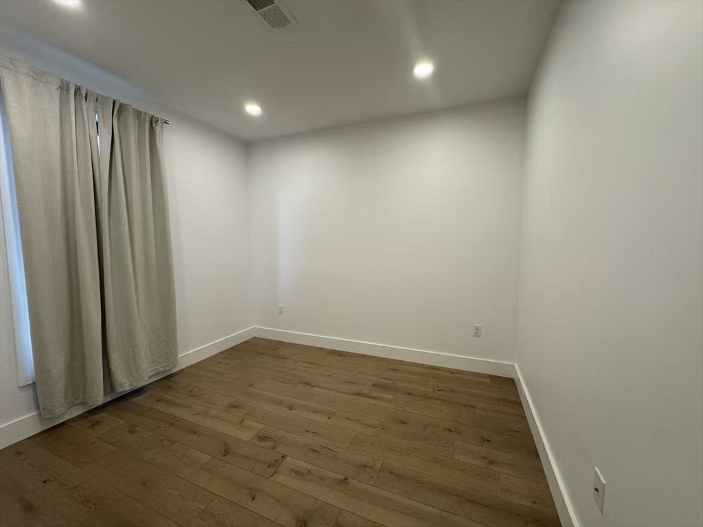 30 Penniman Road, Unit 307 Boston, MA 02134 - Photo 6 of 10 en empty room with wooden floor