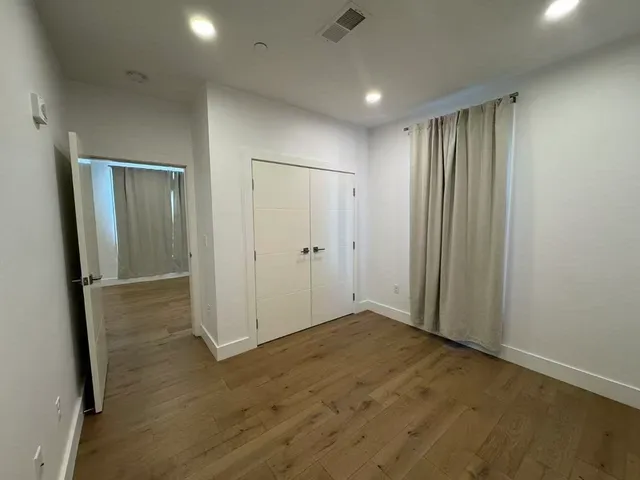 an empty room with wooden floor and closet area
