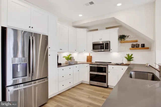 a kitchen with granite countertop white cabinets and stainless steel appliances