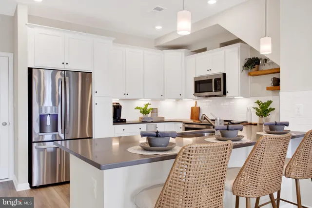 a kitchen with stainless steel appliances a refrigerator a stove a sink dishwasher a dining table and chairs with wooden floor