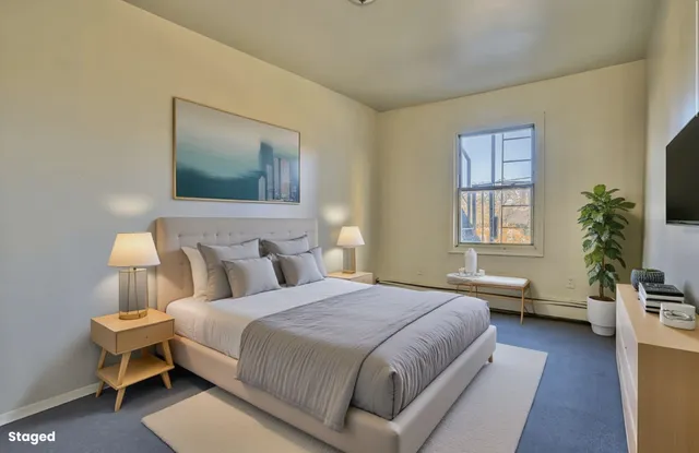 a bedroom with a bed and a potted plant next to a window