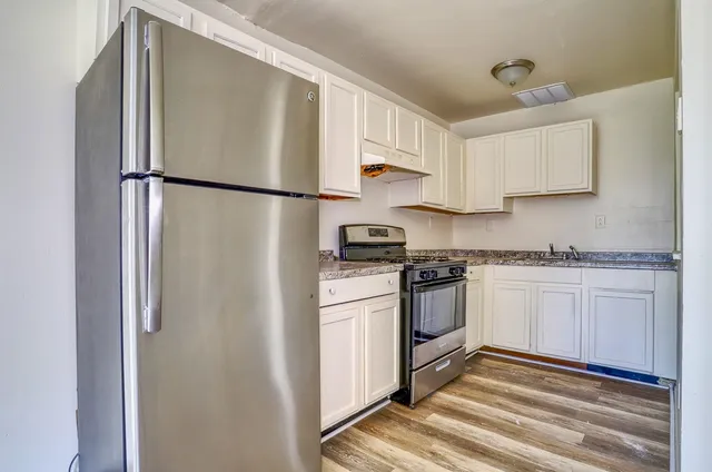 a kitchen with a refrigerator and white cabinets