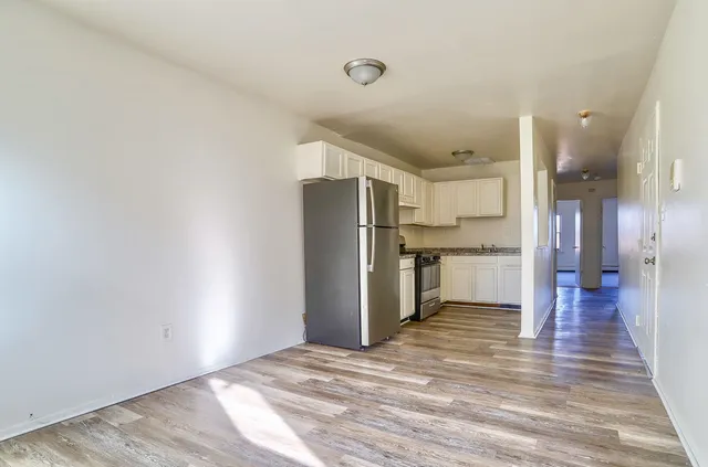 a view of a kitchen with refrigerator and wooden floor