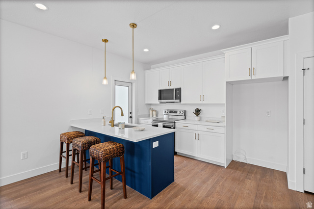 340 East 7635 S Street Sandy, UT 84047 - Photo 6 of 32 Dual tone kitchen with a kitchen breakfast bar, a peninsula, dark wood-style flooring, stainless steel appliances, and decorative light fixtures