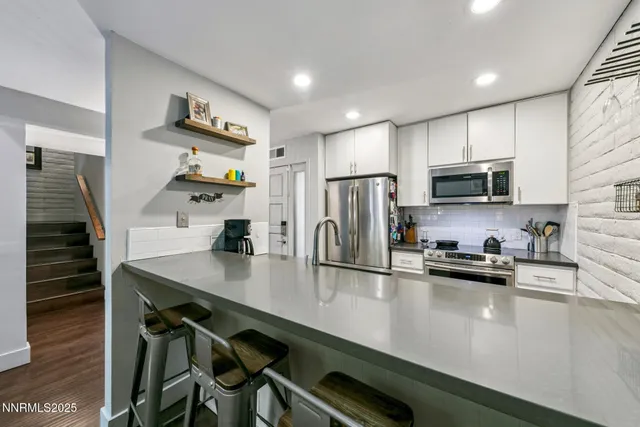 a kitchen with stainless steel appliances granite countertop a sink dishwasher and a stove with wooden floor
