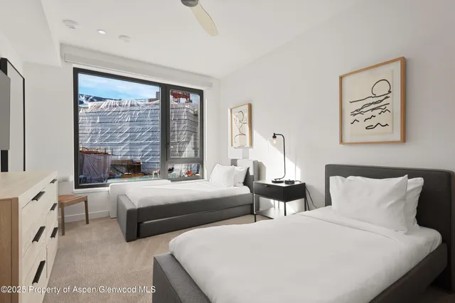 a bedroom with two beds and a large window