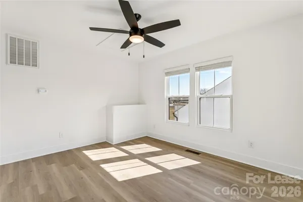 an empty room with wooden floor and windows