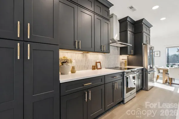 a large kitchen with stainless steel appliances a large counter top a sink and a wooden floor