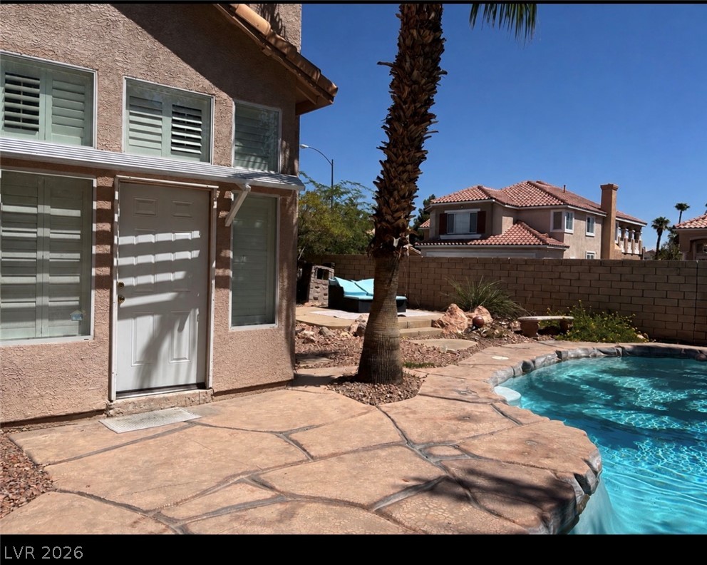 7815 Windward Road Las Vegas, NV 89147 - Photo 11 of 13 An inviting backyard features a custom stone patio surrounding a sparkling pool under clear skies.