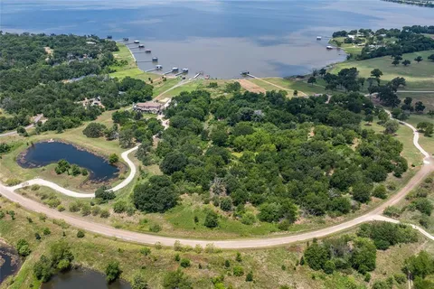 an aerial view of a residential houses with outdoor space and trees