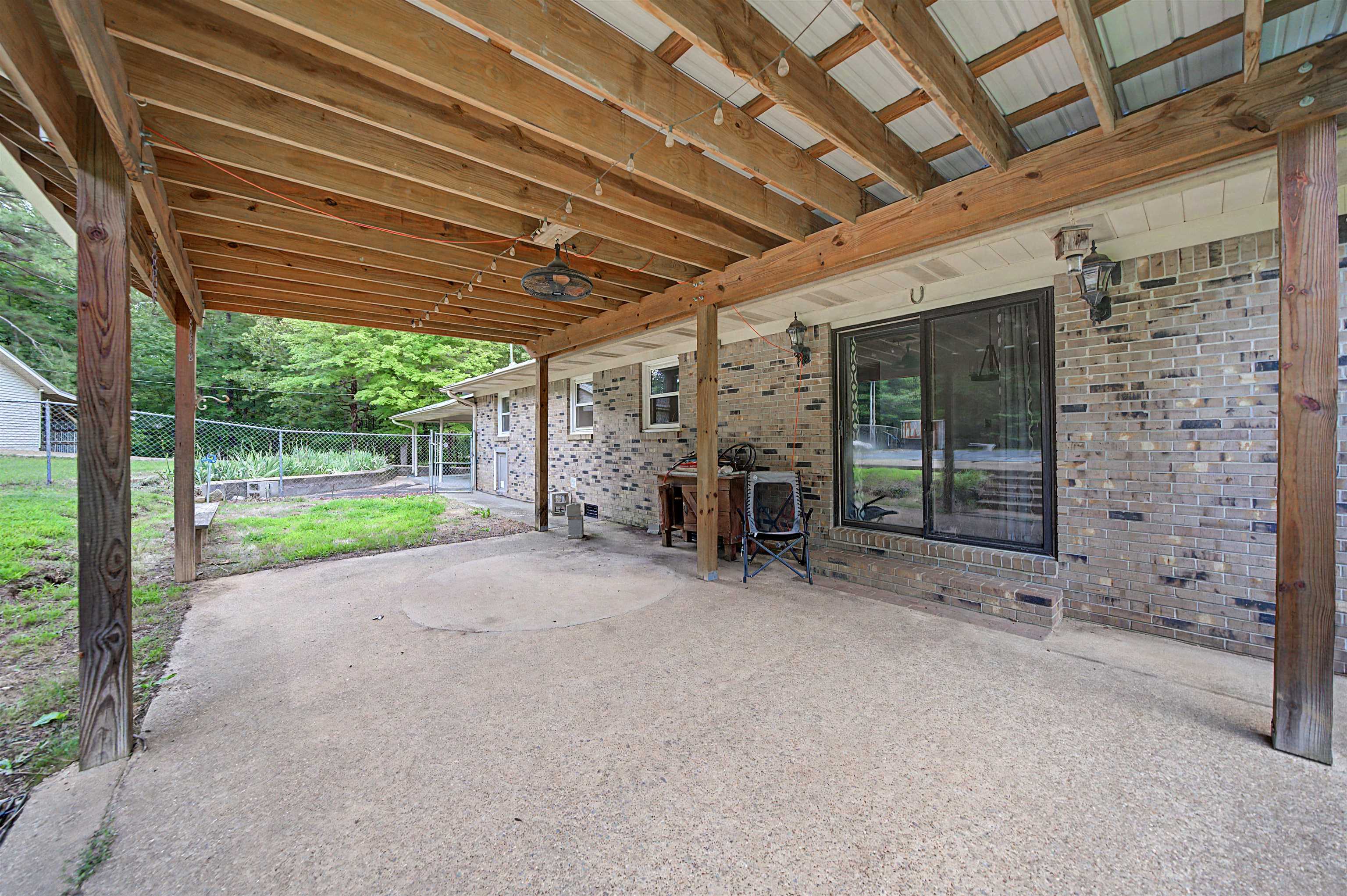 436 Skyline Road Selmer, TN 38375 - Photo 13 of 40 Covered patio featuring a concrete surface, exposed wood beam ceiling, and two exterior wall sconces