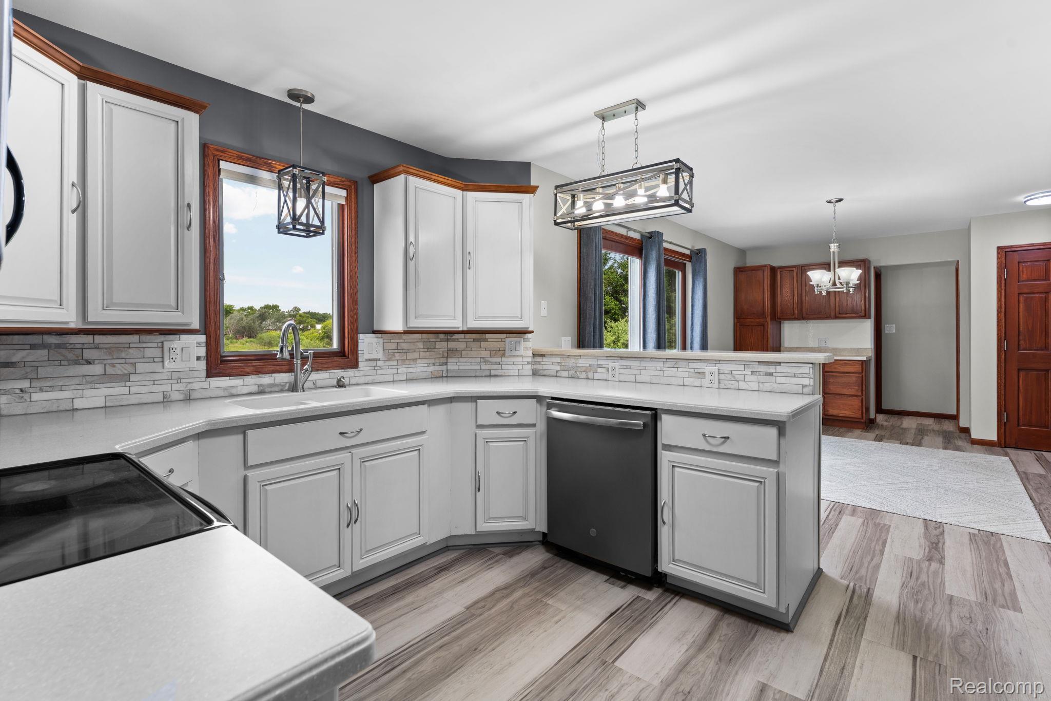 2381 Burke Road Fowlerville, MI 48836 - Photo 7 of 31 Kitchen featuring white cabinetry, light-toned countertops, tile backsplash, and lvp.