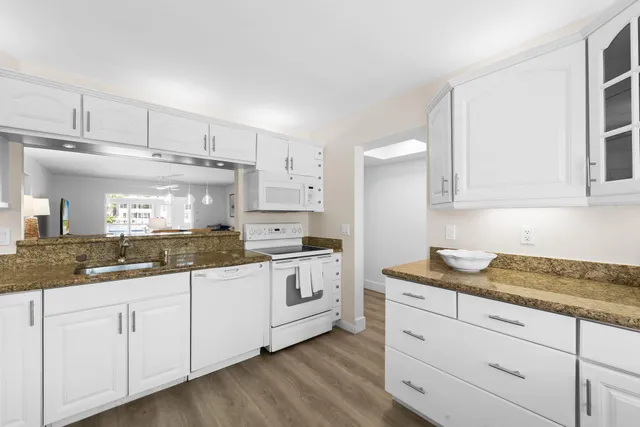a kitchen with granite countertop white cabinets and white appliances