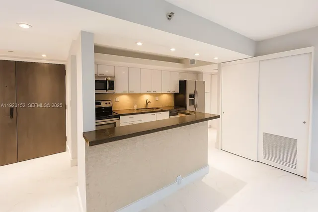 a large kitchen with granite countertop a refrigerator and a sink