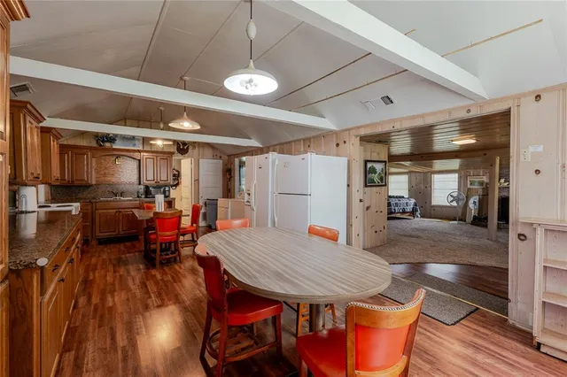 a kitchen with stainless steel appliances granite countertop a stove a refrigerator a sink dishwasher a dining table and chairs with wooden floor