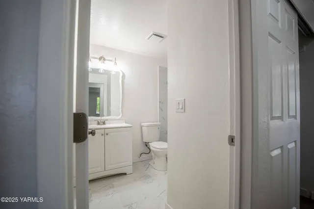 a bathroom with a granite countertop toilet and a sink