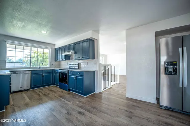 a kitchen with stainless steel appliances kitchen island granite countertop a refrigerator sink and wooden cabinets