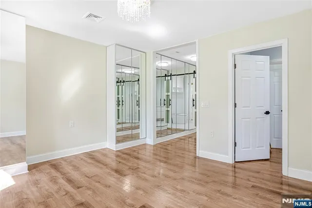 a view of an empty room with wooden floor and a large window