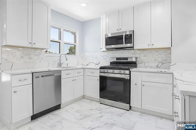 a kitchen with white cabinets stainless steel appliances and sink