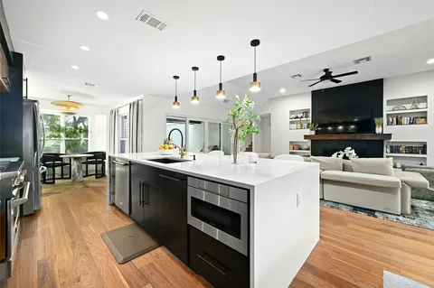 a large kitchen with stainless steel appliances a large counter top a stove and a wooden floors