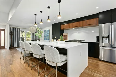 a kitchen with kitchen island granite countertop a sink and a refrigerator