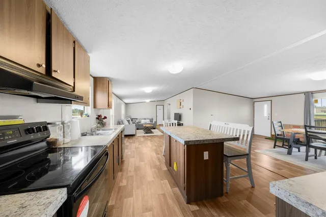 a kitchen with stainless steel appliances granite countertop a stove oven a dining table and chairs with wooden floor