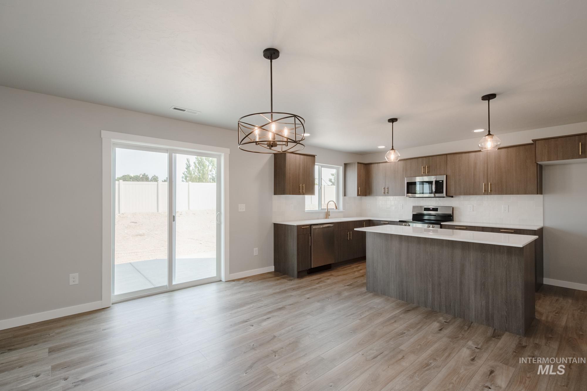 3304 West Morere Drive Meridian, ID 83642 - Photo 10 of 28 Kitchen featuring a chandelier, tasteful backsplash, a center island, pendant lighting, and appliances with stainless steel finishes