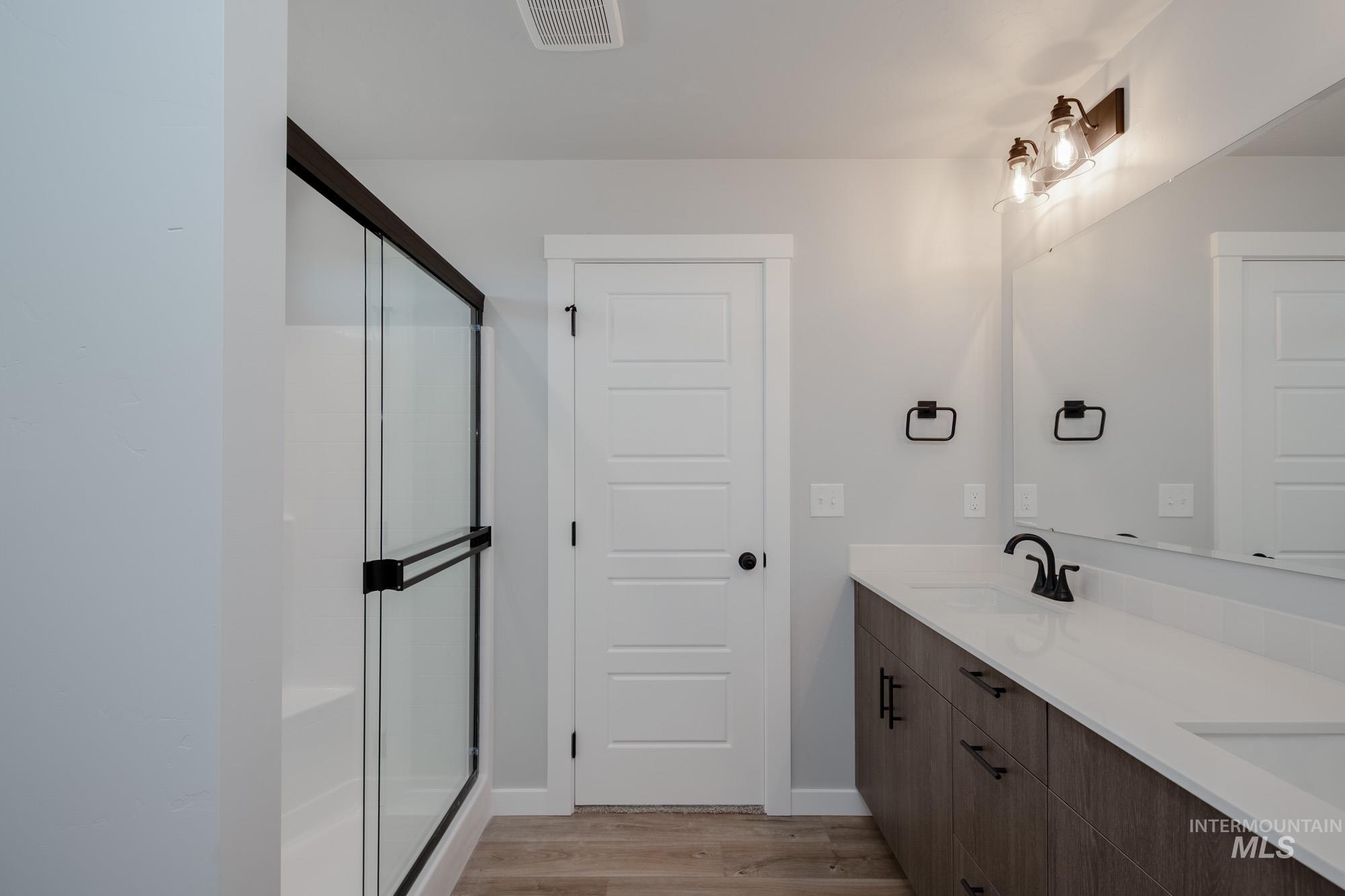 3304 West Morere Drive Meridian, ID 83642 - Photo 20 of 28 Bathroom featuring light wood-style floors, double vanity, and a shower stall