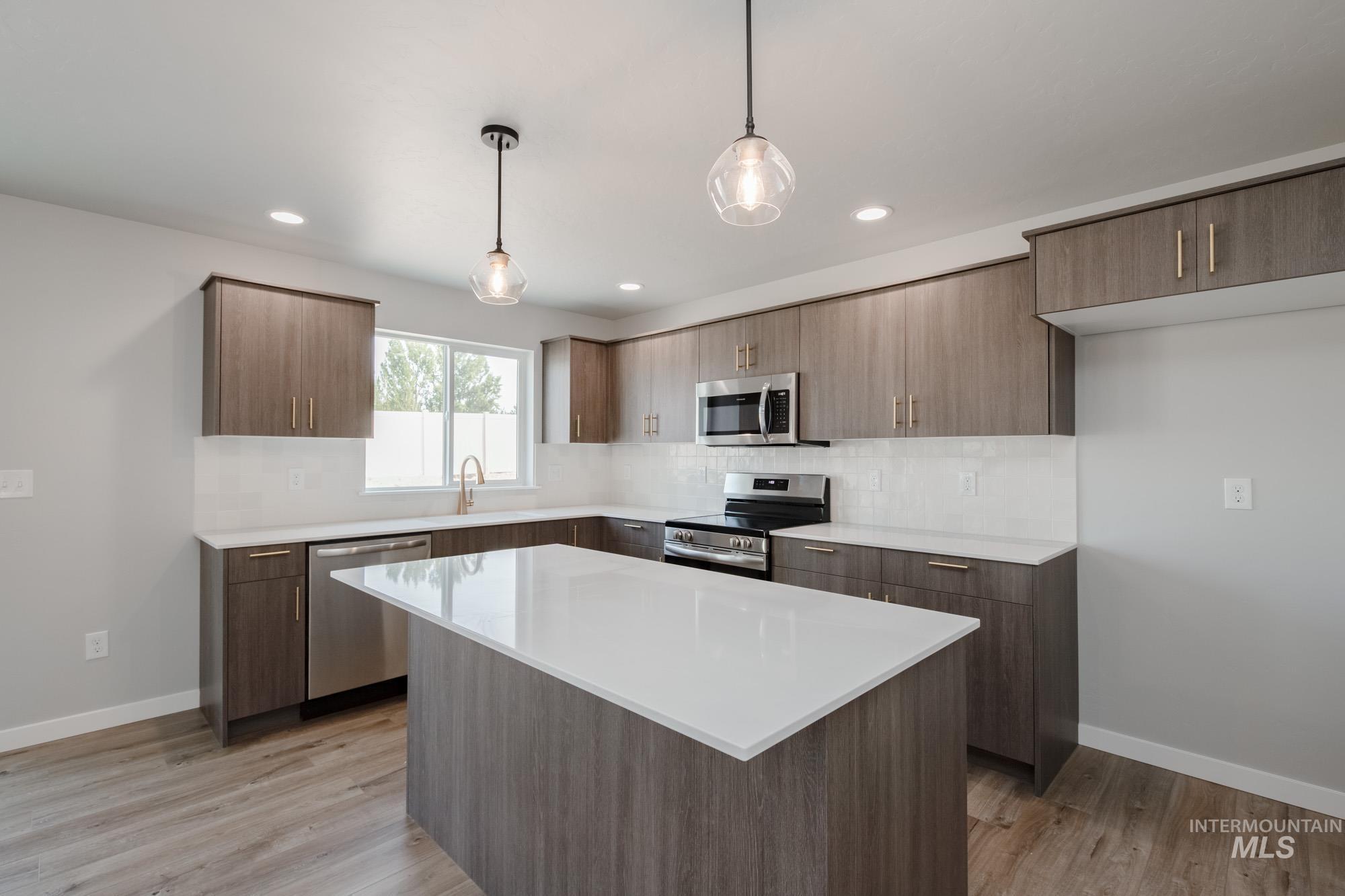 3304 West Morere Drive Meridian, ID 83642 - Photo 4 of 28 Kitchen with tasteful backsplash, stainless steel appliances, pendant lighting, modern cabinets, and light wood-style flooring