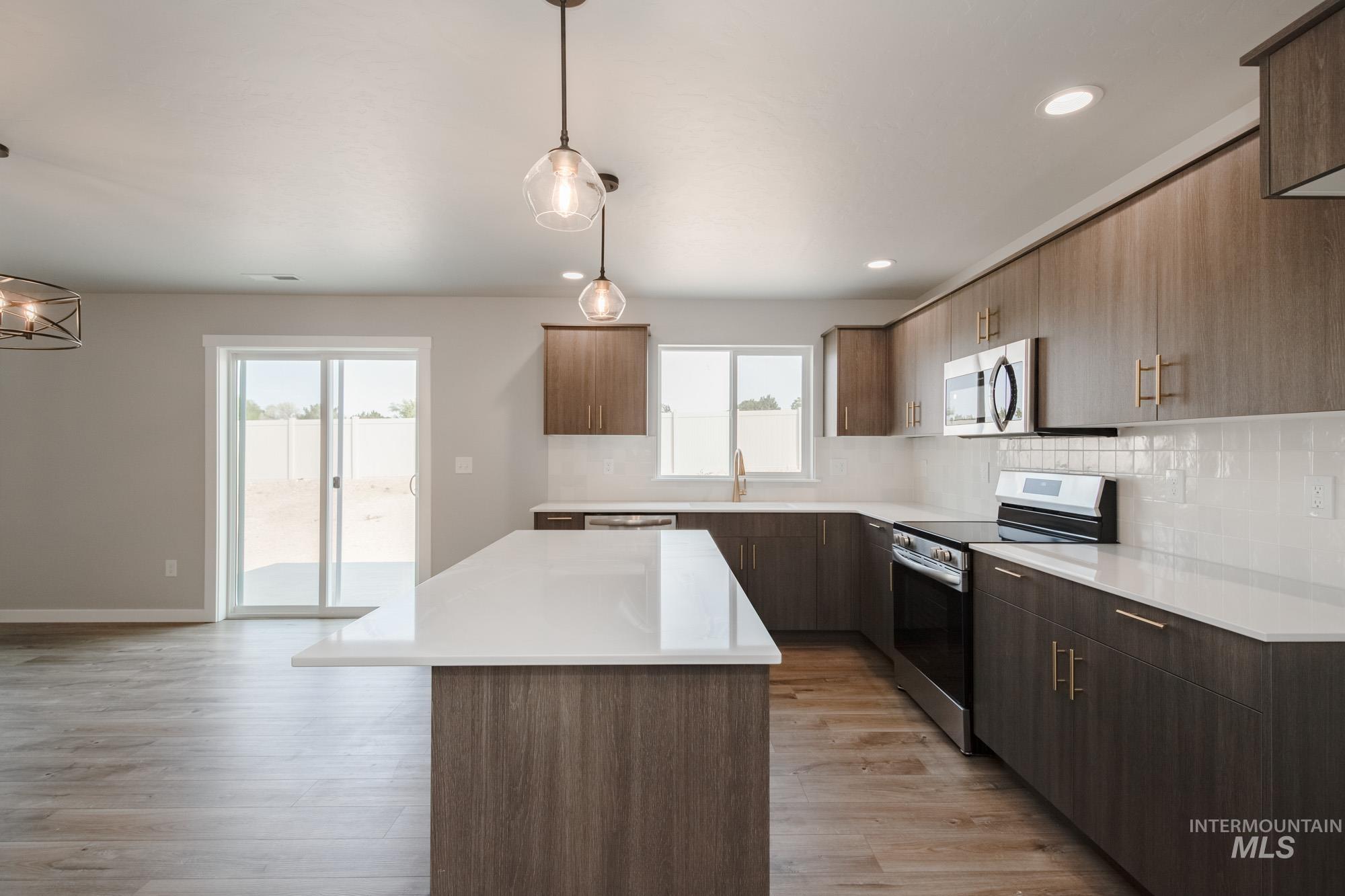 3304 West Morere Drive Meridian, ID 83642 - Photo 9 of 28 Kitchen featuring tasteful backsplash, appliances with stainless steel finishes, a center island, light wood-style flooring, and decorative light fixtures