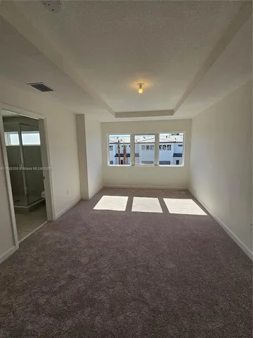 an empty room with floor to ceiling windows and fireplace