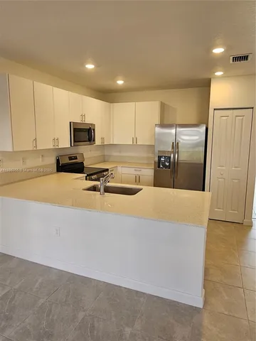 a kitchen with stainless steel appliances a refrigerator a stove a microwave a sink and white cabinets