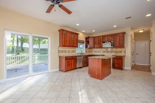 a kitchen with stainless steel appliances granite countertop a stove top oven a sink dishwasher a refrigerator and a dining table with wooden floor