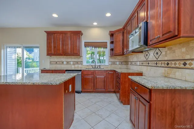 a kitchen with stainless steel appliances granite countertop wooden cabinets a sink and dishwasher a stove top oven with wooden floor