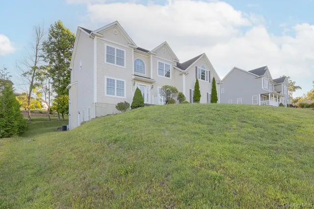a view of a white house next to a yard with big trees
