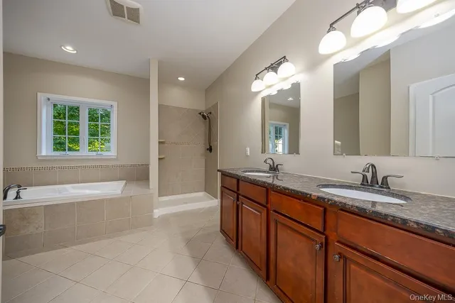 a spacious bathroom with a bathtub sink and mirror