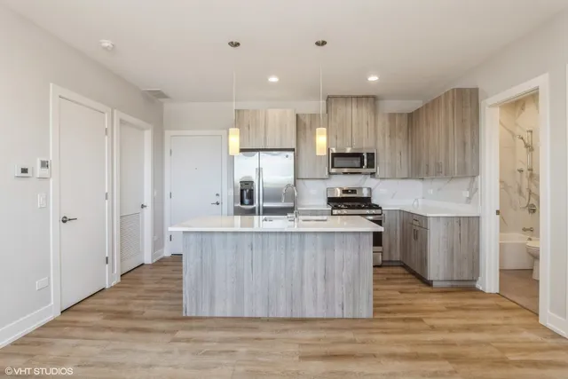 a kitchen with stainless steel appliances granite countertop a stove a sink dishwasher and a refrigerator with wooden floor