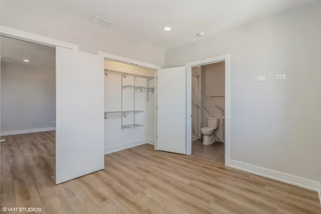 a view of an empty room with wooden floor and closet
