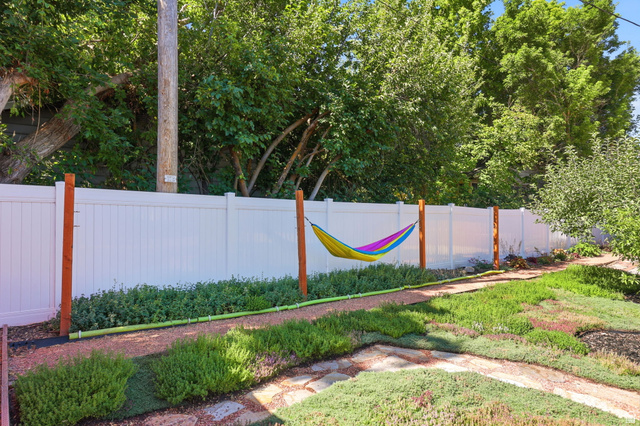 1180 North 400 East Bountiful, UT 84010 - Photo 40 of 50 Fenced backyard featuring a gravel path, ground cover landscaping, mature trees, and a white privacy fence