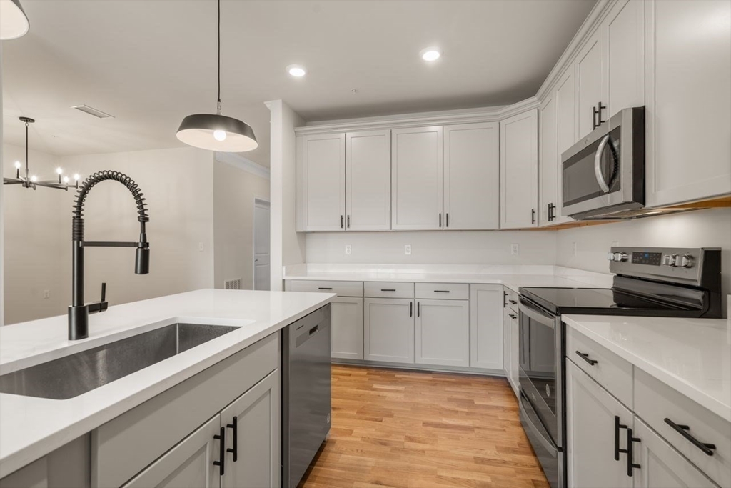 4 Stratton Drive, Unit 308 Woburn, MA 01801 - Photo 16 of 24 a kitchen with a sink stainless steel appliances and white cabinets