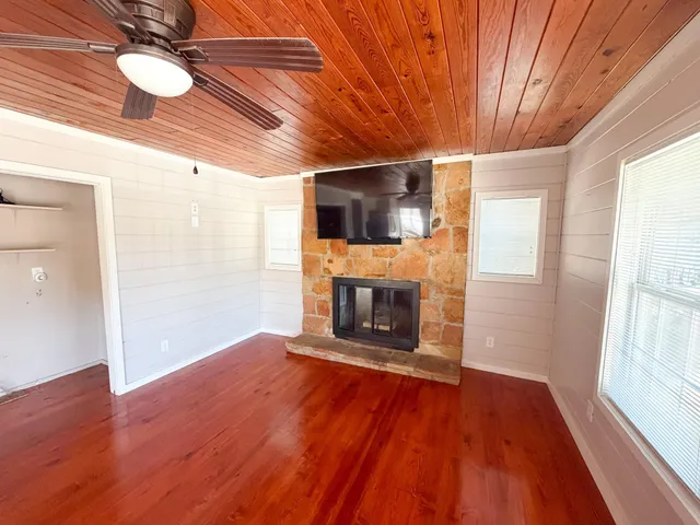a view of a livingroom with a fireplace a ceiling fan and wooden floor