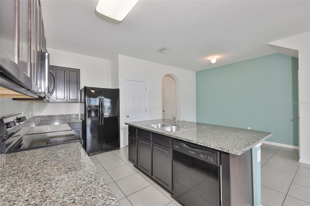 8969 Indigo Trail Loop Riverview, FL 33578 - Photo 15 of 41 a kitchen with stainless steel appliances granite countertop a sink stove and refrigerator