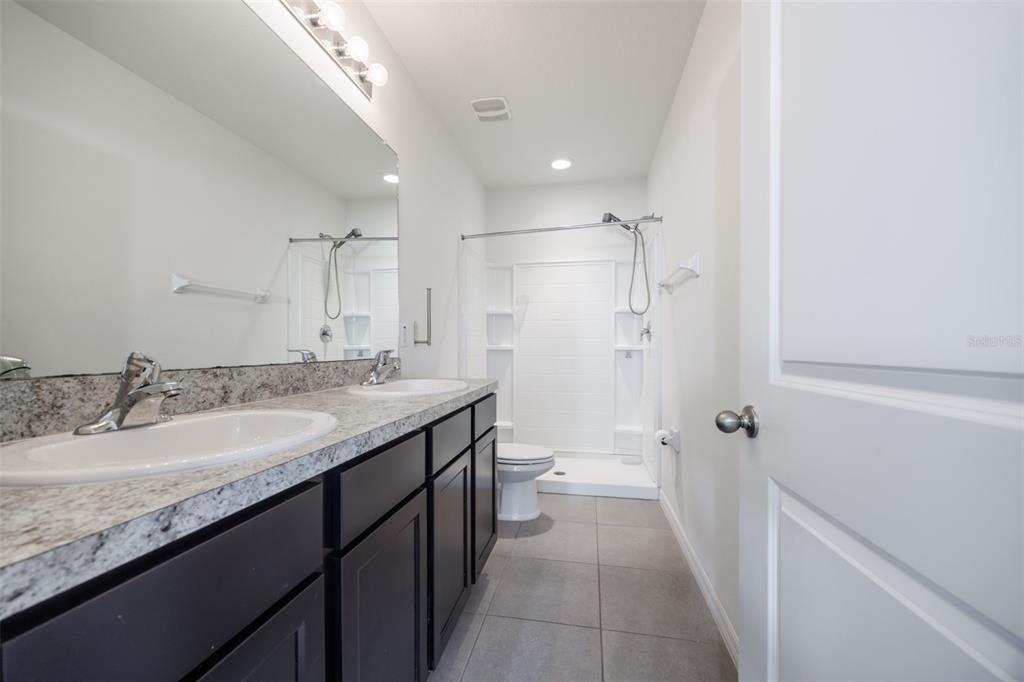 8969 Indigo Trail Loop Riverview, FL 33578 - Photo 27 of 41 a bathroom with a granite countertop sink a toilet a shower and a mirror