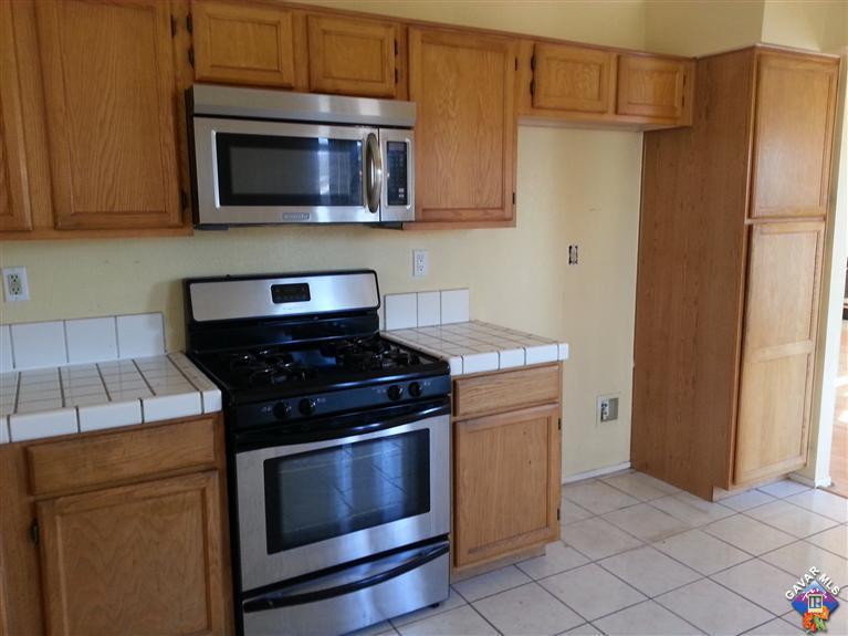 37033 Boxleaf Road Palmdale, CA 93550 - Photo 2 of 15 a kitchen with stainless steel appliances wooden cabinets and a stove top oven